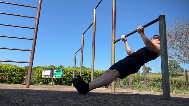 homem pratica exerc&iacute;cios em barras no parque 