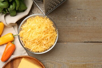 Grated cheese, grater and products on wooden table, flat lay. Space for text