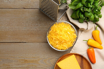 Grated cheese, grater and products on wooden table, flat lay. Space for text