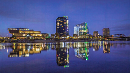 Wide angle nightscape, cityscape of Saskatoon River Landing area with beautiful water reflections.