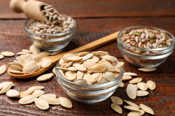 Different seeds in bowls on wooden table, closeup