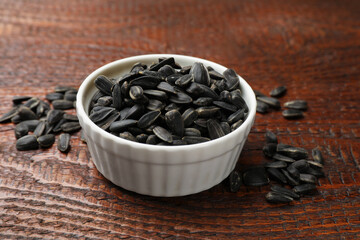 Sunflower seeds in bowl on wooden table, closeup