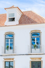 Whitewashed building with blue-trimmed windows and a terracotta tiled roof in Portugal.