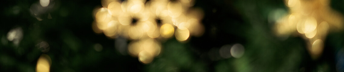 Ultra wide banner with golden blurry christmas ornaments in christmas tree, bokeh xmas chain lights...