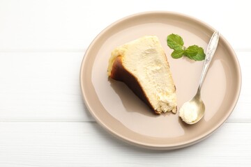Piece of delicious Basque cheesecake with mint on white wooden table, above view. Space for text