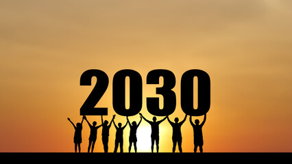 A group of people standing silhouette raising a 2030 sign against the sunset, representing vision...