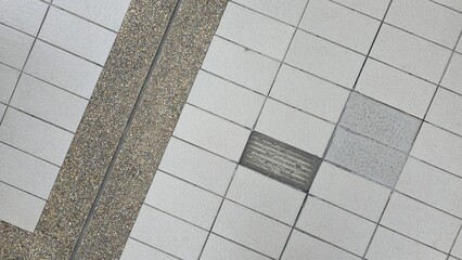 Gray tile and pebble wash floor surface with slight aging and wear marks, showing contrast between smooth and rough textures. Ideal for background or architectural design use.