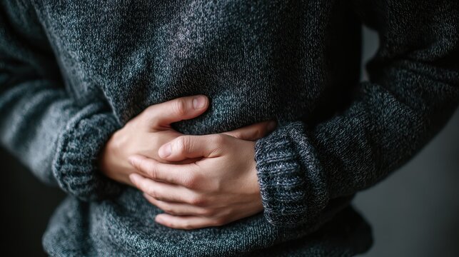 A person clutches their stomach suggesting intestinal issues like blockage or infection possibly related to colitis or ulcers