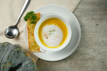 Delicious pumpkin soup served in a bowl with a slice of bread and parsley