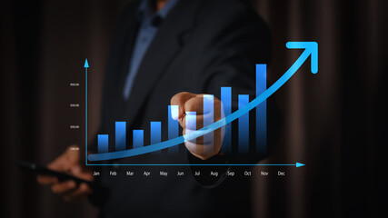 A businessman raising his fist in success and pointing at a rising financial chart, illustrating market growth and business success.