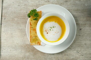 A delicious pumpkin soup in a bowl with garlic bread and parsley garnish