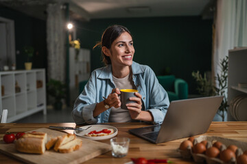 Woman working remotely, enjoying breakfast, smiling at home