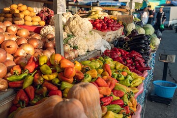 A vibrant display of fresh vegetables including peppers, onions, and cauliflower at a bustling market stall, showcasing the abundance of nature's produce.