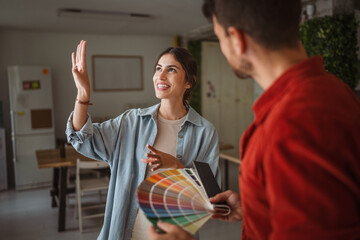 Woman choosing paint color with interior designer holding color palette