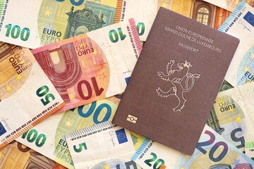 Luxembourg passport lies on big amount of euro money banknotes close up. Rich life and travel in Europe concept