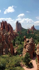 Tall red rock formations and green trees under a blue sky, a scenic outdoor vista
