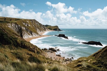 Coastal vista; cliffs, sea, sand, clouds, and natural formations under a bright sky