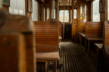 Interior of an old wooden tram with vintage wooden benches, floorboards, and classic details, evoking nostalgia and historic public transport atmosphere.