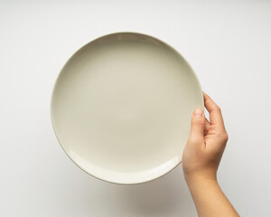 Elegant hand gracefully presents a minimalist ceramic dinner plate, perfect for food styling and modern culinary presentations.