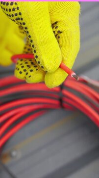 A gloved hand holds a cut wire, highlighting electrical work and safety. Vertical video.
