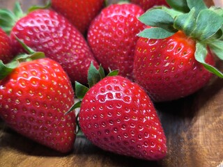 uicy ripe beautiful strawberries in a wooden plate on the table