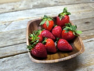 uicy ripe beautiful strawberries in a wooden plate on the table