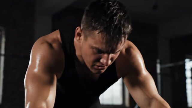 Fit man is pushing himself through a challenging cardio workout on a stationary bike. His determined look and strong muscles convey the intensity of his efforts