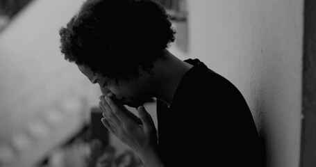 African American boy leaning against a wall, covering his face with hands, overwhelmed with sadness and loneliness, symbolizing childhood depression and isolation