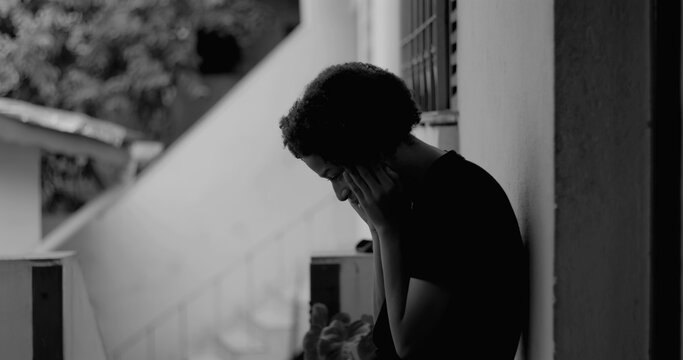 African American boy standing alone by a wall, head bowed in sadness and despair, representing themes of childhood loneliness and emotional vulnerability