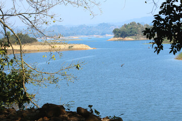Green Hills and Sparkling Lake under Blue Sky
