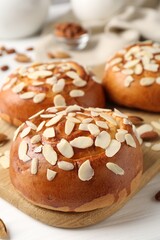 Tasty roll buns with almond flakes and nuts on white wooden table, closeup