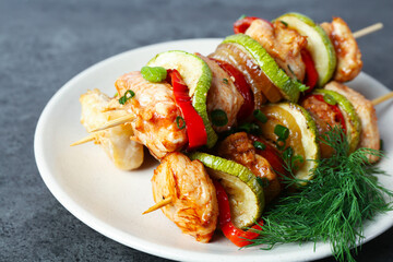 Tasty skewers with chicken, vegetables, dill and green onion on grey table, closeup