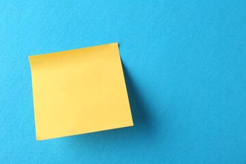 Blank orange note on light blue background, top view. Space for text