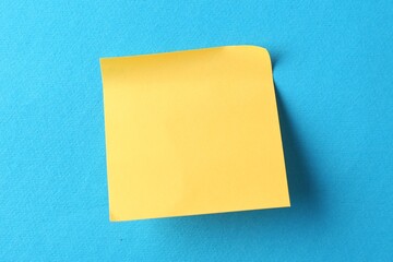 Blank orange note on light blue background, top view. Space for text