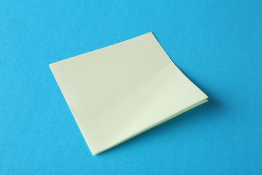 Blank yellow notes on light blue background, closeup. Space for text