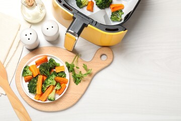 Grilled vegetables and air fryer on white wooden table, flat lay. Space for text