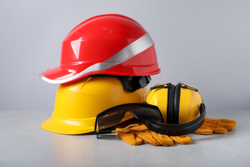 Hardhats, protective goggles, gloves and earmuffs on light background. Safety equipment