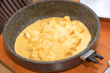 Batter with orange pieces in deep skillet ready for baking orange pie, perfect for dessert recipes and cooking blogs