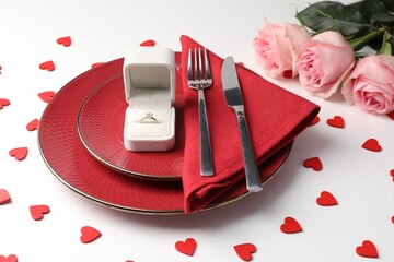 Beautiful table setting for romantic dinner, box with engagement ring and roses on white background