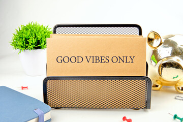 Colorful workspace features a note holder that says good vibes only, surrounded by plants and decorative items, creating an inviting atmosphere for creativity and positivity