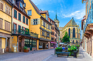 Fototapeta premium Old houses half-timbered style colorful facade, medieval buildings shutters windows on Rue de l'Église street, Saint-Martin church in old town Colmar city historic centre, Alsace region, France