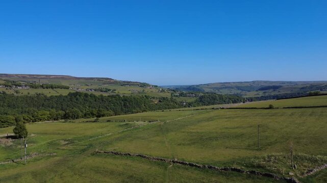 scenic aerial drone view the valley of hebden dale surrounded by trees and hebden bridge and the village of old town and moorland in the distance