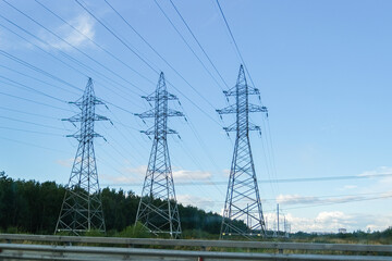 High power transmission towers with power lines against a clear blue sky. Electricity supply infrastructure for energy concept.
