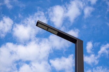Modern street lighting pole with rectangular LED lamp against blue sky. Use for urban lighting systems, street infrastructure, architectural design, and city planning projects. Real photo