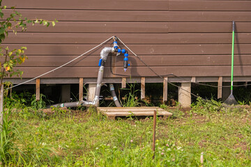 Irrigation system pipes installed along a rural building wall. Home garden watering setup for agriculture farm. Plumbing renovation background.