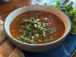A hearty bowl of Vietnamese beef stew, Bo Kho, served with a fresh baguette and herbs