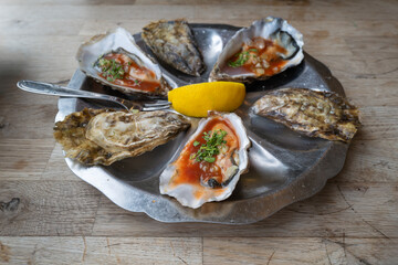 Shallow focus on one of three prepared oysters with horse raddish and tobasco and dressed with parsley. The Red sauce is eye catching in the oyster shells.