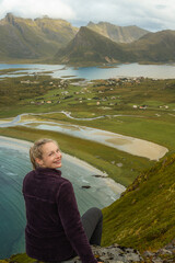 Fototapeta premium Young beautiful woman resting at a hill with beach and lakes in the background