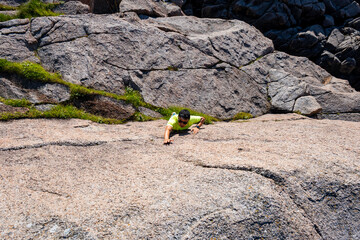 young man freeclimbing up or bouldering, rockclimbing the rock outdoor