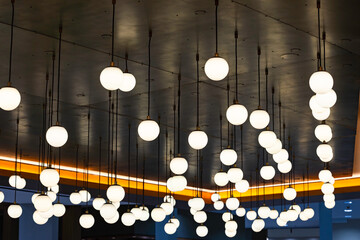 Numerous glowing spherical hanging chandeliers on the ceiling.